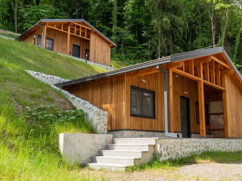 Holz-Ferienhäuser an einem bewaldeten Hang im Sommer